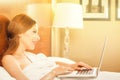 Woman laying in bed relaxing using working on laptop computer Royalty Free Stock Photo