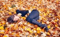 Woman laying down on the pile of leafs and playing. Royalty Free Stock Photo