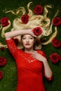 Woman laying in grass wearing red dress holding a rose Royalty Free Stock Photo