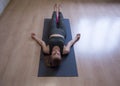 Woman laying on gray mat in relaxing pose on the floor, yoga class, front view Royalty Free Stock Photo