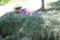 Woman laying in the hay. Putting the grass on the trailor. Farm chores, working on a field.