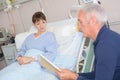 woman laying on hospital bed while dad reading Royalty Free Stock Photo