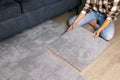 woman laying self adhesive carpet tiles on floor in living room