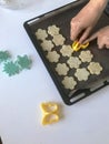 A woman is laying a shortbread cookie with sesame on a baking sheet. Before shipment to the oven. Nearby lie molds for shaping the