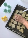 A woman is laying a shortbread cookie with sesame on a baking sheet. Before shipment to the oven. Nearby lie molds for shaping the