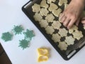 A woman is laying a shortbread cookie with sesame on a baking sheet. Before shipment to the oven. Nearby lie molds for shaping the