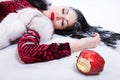 Woman laying on a snow near the bitten apple