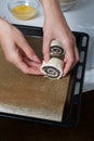 A woman lays curls filled with poppy and walnuts on a baking sheet. Nearby on the table are ingredients and tools