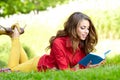 Woman lays on green field and reads book. Royalty Free Stock Photo