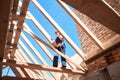 Woman lead architect climbing up on roof wooden construction to check quality