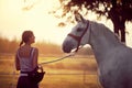 Woman leading her horse after a ride. Training on countryside, sunset golden hour. Freedom nature concept