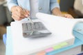 Woman leafing through folder with documents and looking at calculator closeup