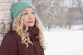 Woman leaning against tree in winter