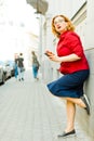 Woman leaning against the wall and using cell phone