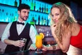 Woman leaning on counter while bartender in background Royalty Free Stock Photo