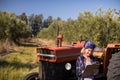 Woman leaning on tractor while writing on clipboard