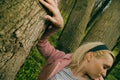 Woman leaning on tree trunk.