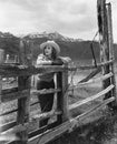 Woman leaning on wooden fence on ranch Royalty Free Stock Photo