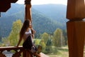 Woman leaning on wooden handrail and enjoys and relaxes beautiful mountain scenic. Young female on terrace sitting on Royalty Free Stock Photo