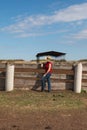 A woman leans on the fence of a corral for cattle, horses on farm and looks into the distance Royalty Free Stock Photo