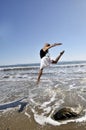 Woman leaping win waves on beach Royalty Free Stock Photo