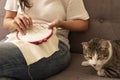 Woman sewing cross stitch with her cats on the sofa at home