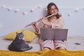 Woman learns music and cat, lifestyle. Girl plays the flute while sitting on yellow bed