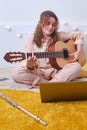 Woman learns music lifestyle. Girl plays the guitar while sitting on yellow bed
