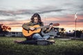 woman learns to play guitar in a park at dusk