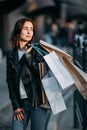 Woman in leather jacket carrying many paper bags