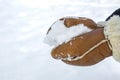 Woman in leather mittens rolls a snowball outdoors, close-up. Hands in warm mittens make snow in winter. Brown leather Royalty Free Stock Photo