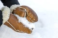 Woman in leather mittens rolls a snowball outdoors, close-up. Hands in warm mittens make snow in winter. Brown leather Royalty Free Stock Photo