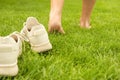 Woman leaving her sneakers and walking away barefoot on green grass, closeup Royalty Free Stock Photo