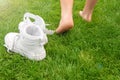 Woman leaving her sneakers and walking away barefoot on green grass, closeup Royalty Free Stock Photo