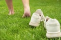 Woman leaving her sneakers and walking away barefoot on green grass, closeup Royalty Free Stock Photo