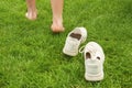 Woman leaving her sneakers and walking away barefoot on green grass, closeup Royalty Free Stock Photo