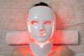 Woman with led light therapy facial and neck beauty mask photon therapy. Home skincare and me time concept