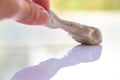 Woman left hand picking up Gum stick or Clay glue stick from white acrylic background, Close up, Creative idea concept