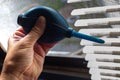 Woman left hand squeezing blue blower for cleaning dust blinds inside a window, Blurred dust and Dirty mosquito wire screen Royalty Free Stock Photo