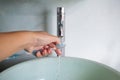 Woman left hand washing toothbrush on green washbasin, Water flowing from faucet, Bathroom concept