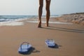 Woman left her beach slippers and walking barefoot on sandy seashore, closeup Royalty Free Stock Photo