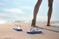 Woman left her beach slippers and walking barefoot on sandy seashore, closeup Royalty Free Stock Photo