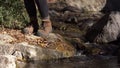 Woman leg crossing a river. Woman jumping on stone and take water from river.