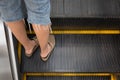 Woman leg standing on a metal escalator staircase.