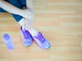 Woman leg wearing purple shoes with bottle of water on wooden floor background. Royalty Free Stock Photo