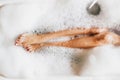 Woman legs in bath foam in spa hotel. Top view Royalty Free Stock Photo