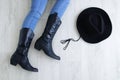 Woman legs in black cowboy boots with cowboy hat. Lying on a gray wooden background Royalty Free Stock Photo