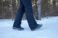 Woman legs in boots close up the snow-covered path in the winter forest, rear view Royalty Free Stock Photo