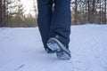 Woman legs in boots close up the snow-covered path in the winter forest, rear view Royalty Free Stock Photo