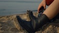 Woman legs in boots sitting on sandy beach. Stylish girl holding smartphone Royalty Free Stock Photo